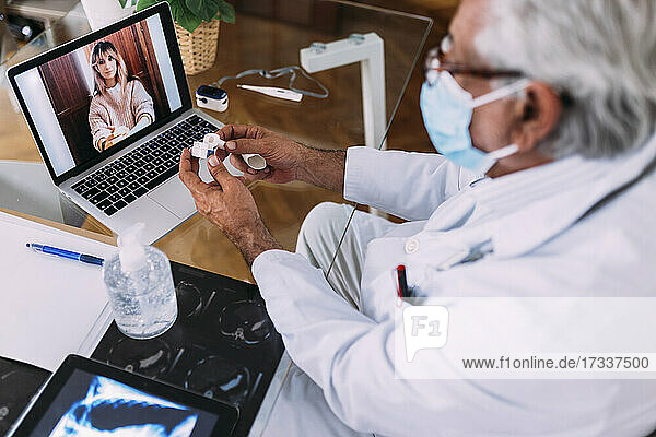 Männlicher Arzt mit Gesichtsschutzmaske bei der Betreuung einer Patientin in der Klinik während COVID-19