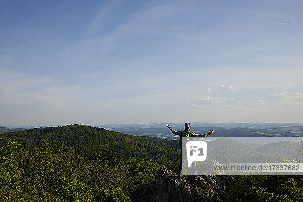 Male hiker standing with arms outstretched on top of mountain