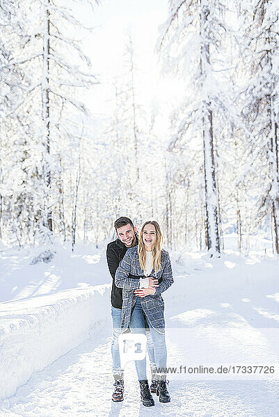 Happy couple embracing on snow during vacation