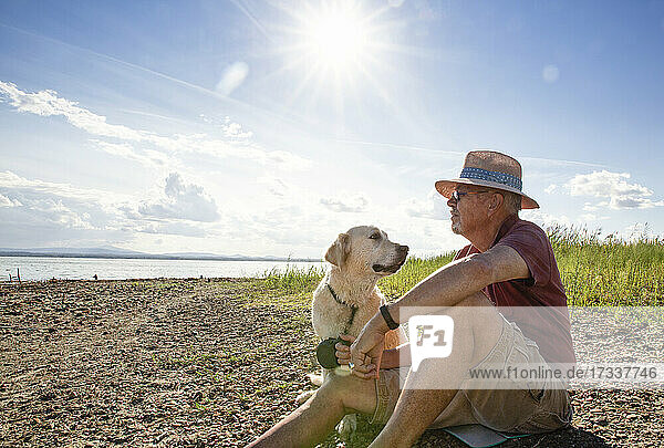 Älterer Mann mit Hund am Trasimeno-See an einem sonnigen Tag