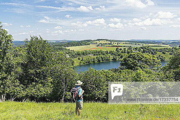 Senior hiker admiring landscape surrounding Weinfelder Maar lake