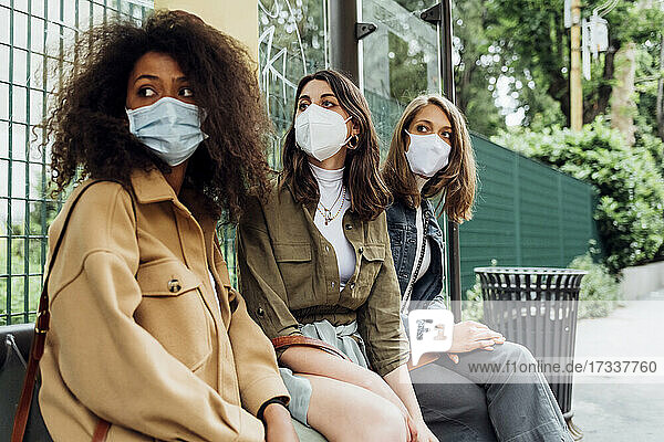 Junge Frauen mit Schutzmaske an der Bushaltestelle