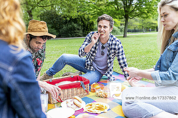 Freunde essen auf einer Picknickdecke sitzend