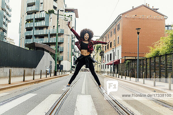 Carefree woman jumping with arms outstretched on railroad tracks