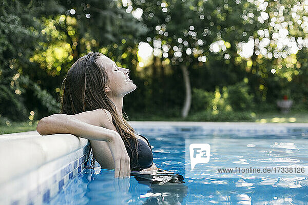 Young woman with eyes closed relaxing at poolside