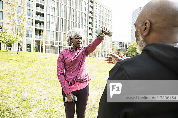 Ältere Frau trainiert mit Hanteln in einem öffentlichen Park