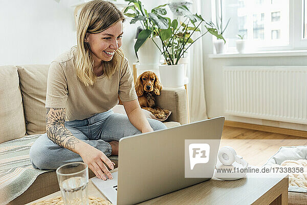 Smiling young female freelancer using laptop in living room
