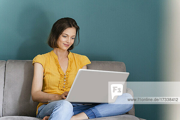 Mittlere erwachsene Frau  die bei der Arbeit zu Hause einen Laptop benutzt