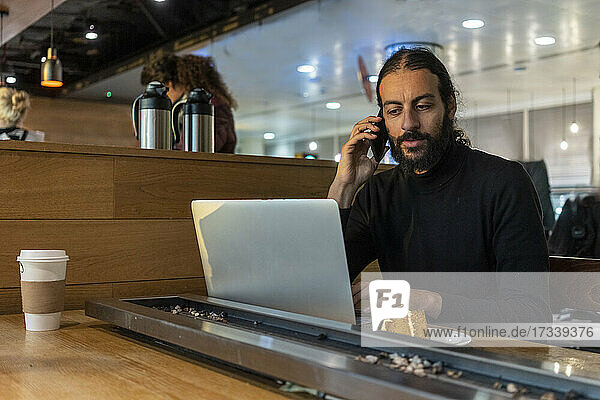 UK  London  Mann mit Laptop und Smartphone im Flughafencafé