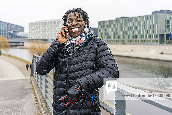Deutschland  Berlin  Lächelnder Mann mit Smartphone in der Stadt