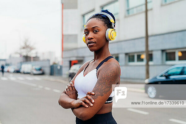 Italien  Mailand  Porträt einer Frau in Sport-BH und Kopfhörer in der Stadt