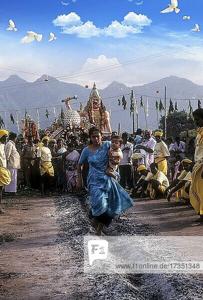 Eine Frau  die ein Kind auf der Hüfte trägt und über brennende Kohle läuft  Feuerlauffest im Vana Badra Kali Amman Tempel in Nellithurai bei Mettupalayam  Tamil Nadu  Indien  Asien