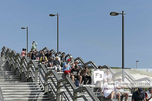 Holidaymakers sitting on wooden steps one behind the other  Wenningstedt beach crossing  Sylt  North Frisian Islands  Schleswig-Holstein  Germany  Europe