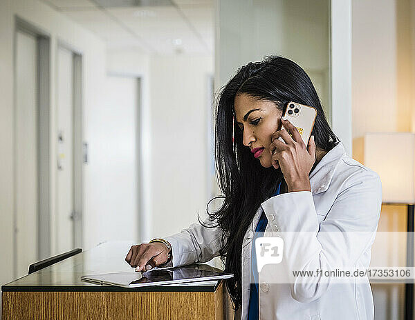 Doctor talking on mobile phone at reception desk