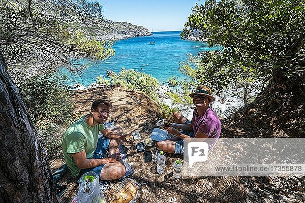 Zwei junge Männer beim Picknick  Bucht mit türkisblauem Wasser  Anthony Quinn Bucht  Faliraki  Rhodos  Dodekanes  Griechenland  Europa