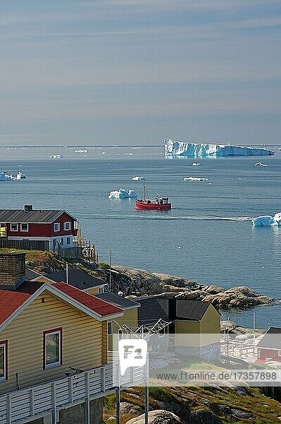Wohnhäuser aus Holz vor einer Bucht mit Fischerboot und Eisbergen  Arktis  Diskobucht  Ilulissat  Grönland  Dänemark  Nordamerika