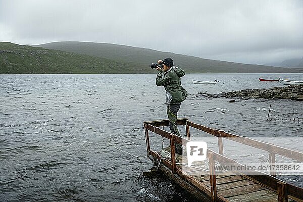Wanderer fotografiert auf einem Holzsteg über dem Leitisvatn See  Vagar  Faroer Inseln