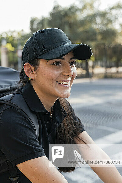 Smiling young essential service worker wearing black cap