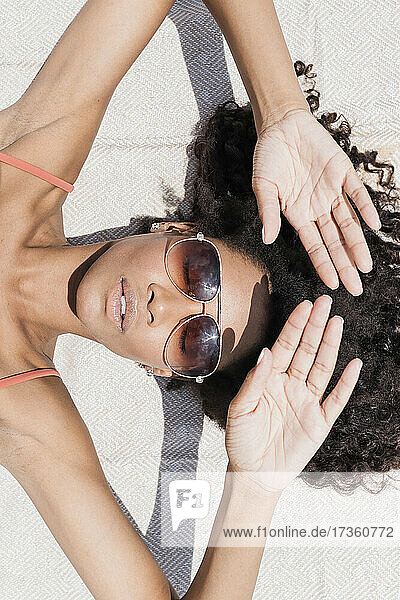 Frau mit Sonnenbrille beim Sonnenbaden am Strand