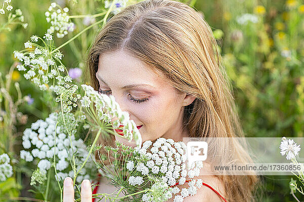 Lächelnde Frau mit geschlossenen Augen  die an Blumen riecht