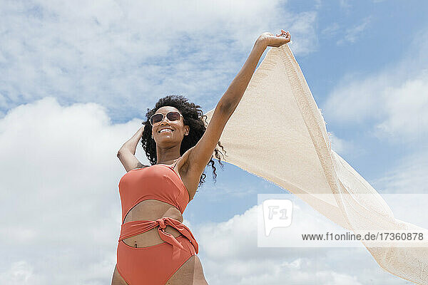 Junge Frau hält Strandhandtuch an einem sonnigen Tag
