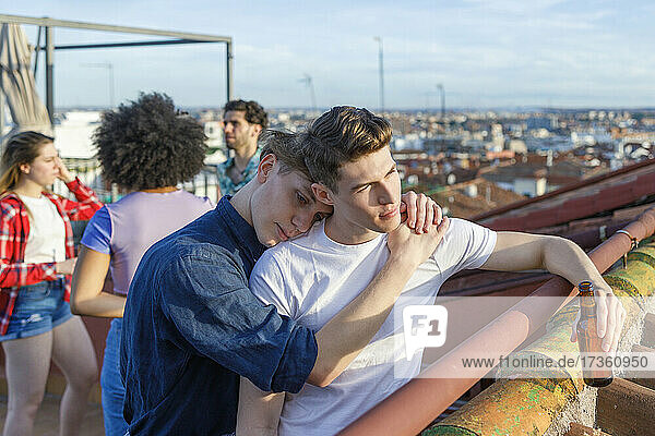 Young man embracing male friend on terrace during party