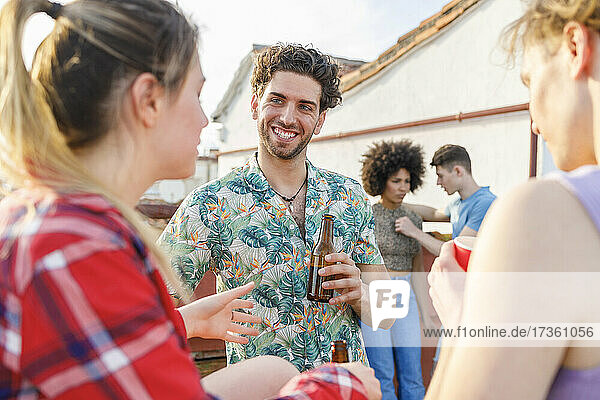 Young male and female friends having drinks on rooftop during party