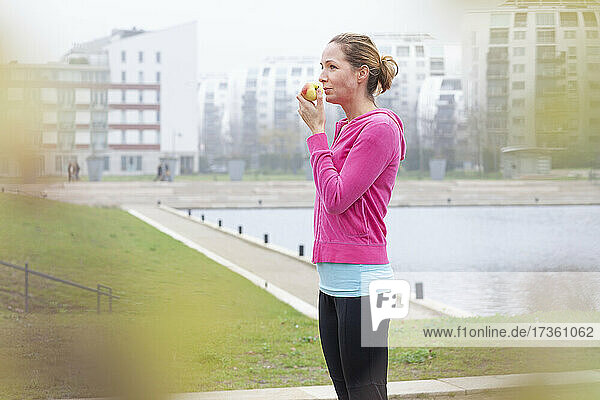 Frau isst Apfel  während sie in der Stadt steht