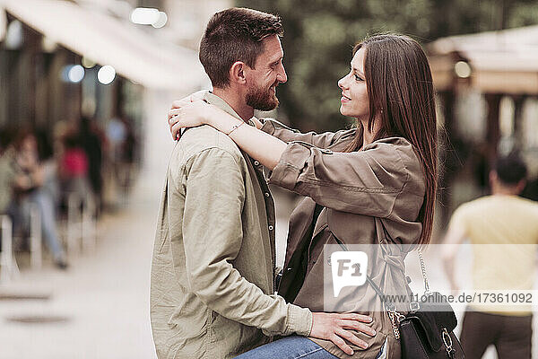 Lächelnde Frau  die den Arm um ihren Freund legt und ihn ansieht