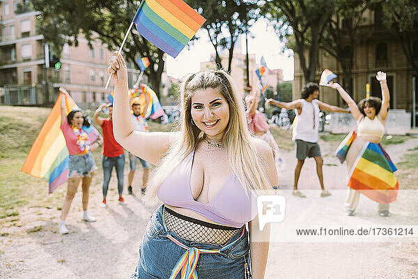 Lächelnde Frau mit Regenbogenfahne im Park