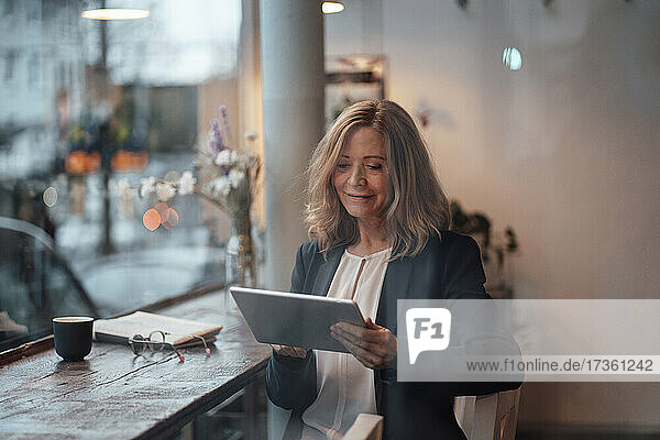Weibliche Fachkraft mit digitalem Tablet in einem Café sitzend