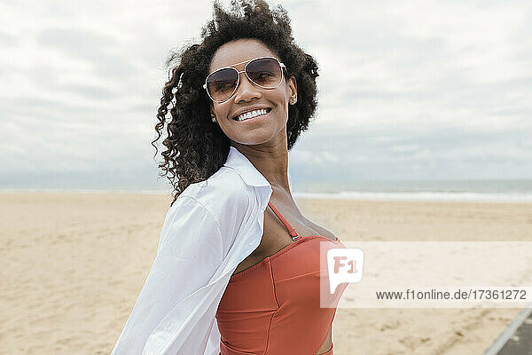Smiling young woman looking away while standing at beach