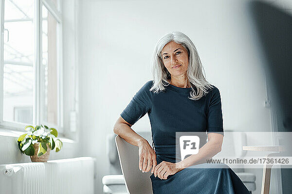 Mature businesswoman sitting on chair at office