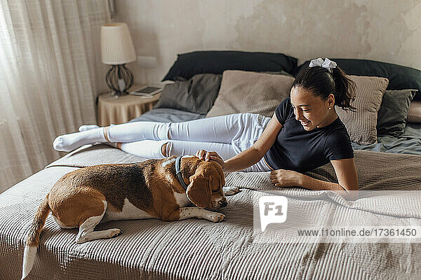Pre-adolescent girl with dog in bedroom at home