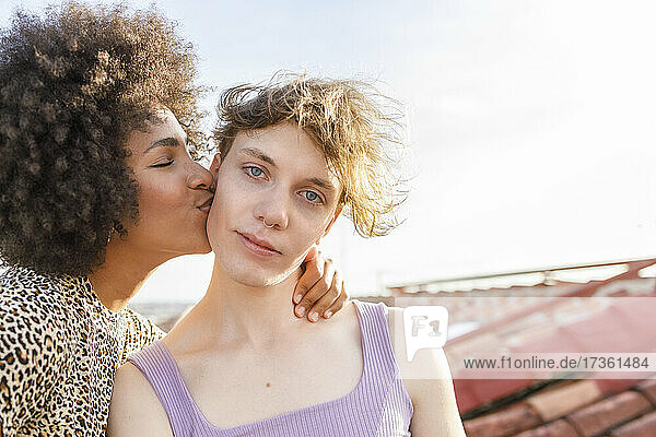 Afro woman kissing male friend on building terrace