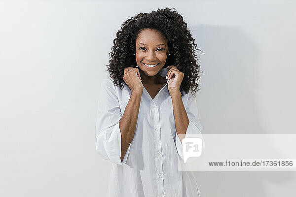 Junge Frau lächelt  während sie ein Halsband vor weißem Hintergrund hält
