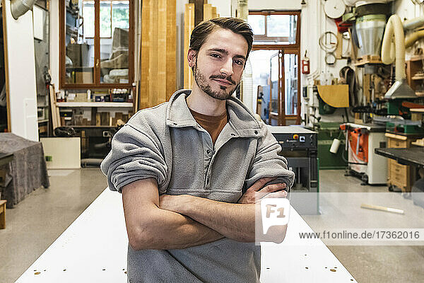 Young male craftsperson with arms crossed at workshop