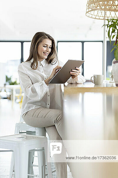 Berufstätige Frau  die im Büro sitzend ein digitales Tablet benutzt