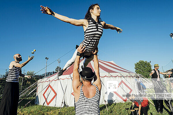 Circus acrobats and artists performing together in front of tent