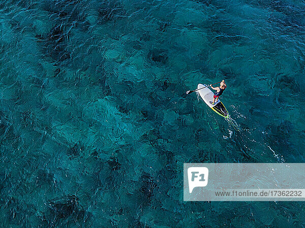 Aerial view of man paddleboarding in blue waters of North Male Atoll