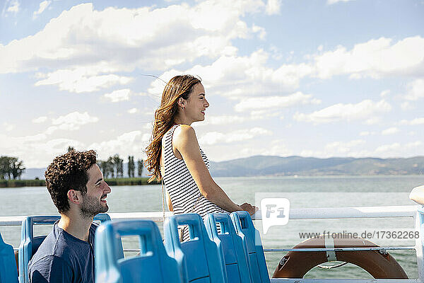 Woman looking at Lake Trasimeno while standing by man in passenger craft