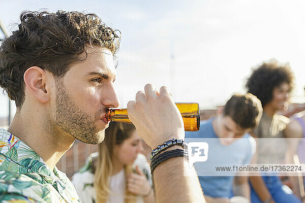 Young man drinking beer during party