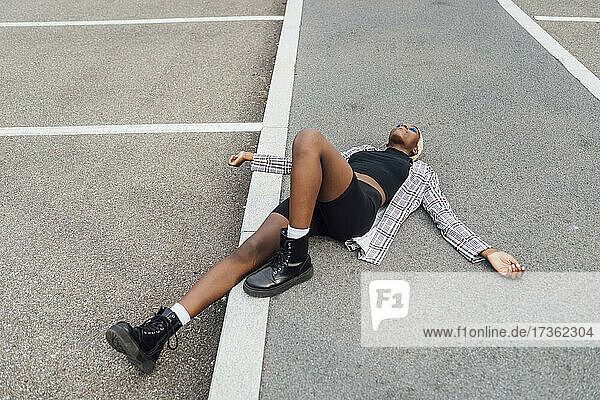 Carefree woman with arms outstretched lying on road in city