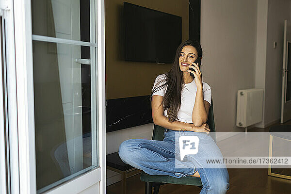 Glückliche schöne Frau  die in einer Wohnung mit ihrem Handy telefoniert