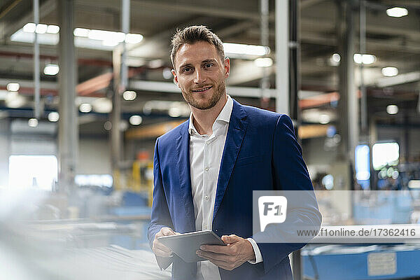 Smiling male professional with digital tablet at industry