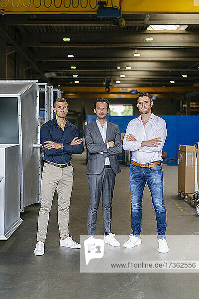 Male professionals with arms crossed standing at industry
