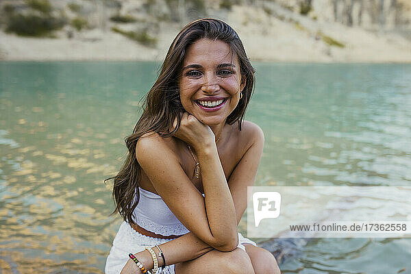 Schöne junge Frau mit Hand am Kinn  sitzend im Pantano de Santa Ana  Castillonroy  Spanien