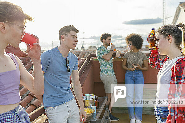 Multiethnische Freunde unterhalten sich bei Getränken auf der Terrasse während einer Party
