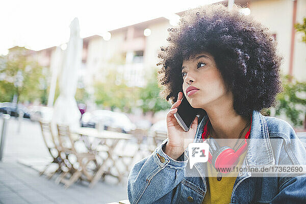 Young woman with afro hairdo on the phone in the city