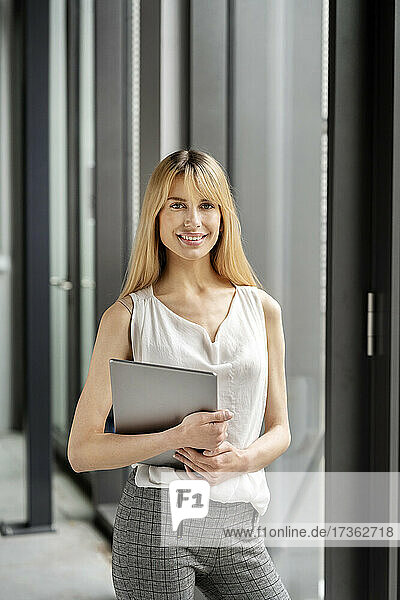 Businesswoman holding laptop at workplace